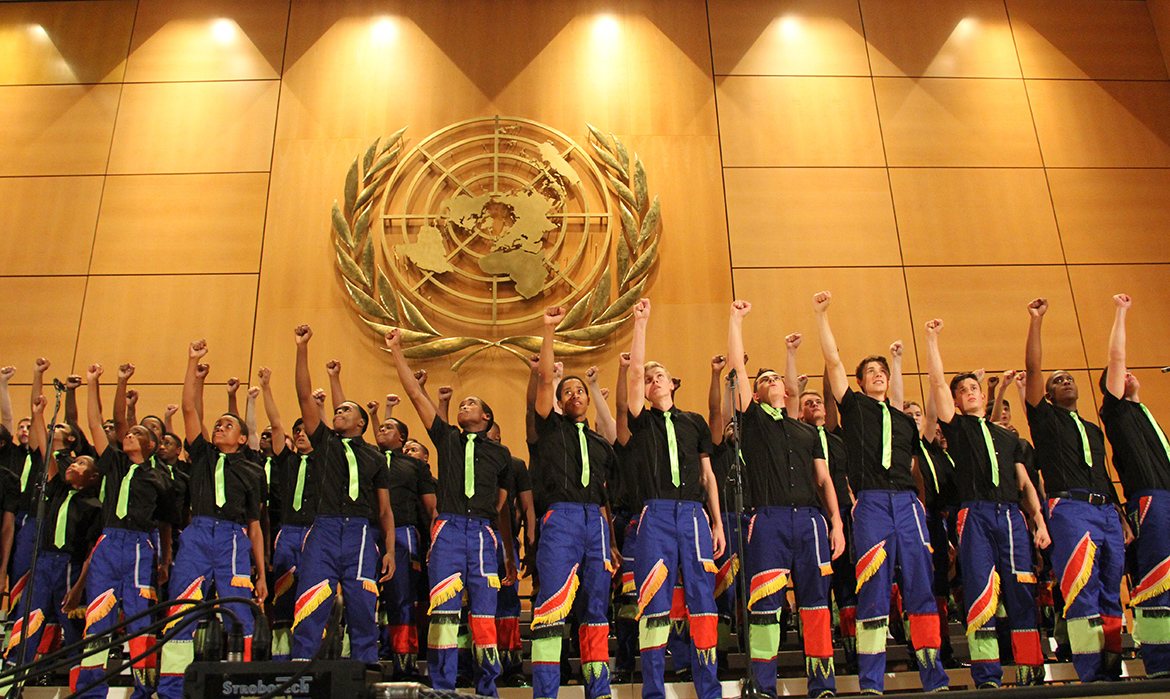 Kearsney College choir performing beneath the United Nations emblem, fists raised